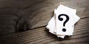 Stack of white cards with a question mark on top sitting on a wood table
