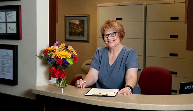 Female administrative staff member standing at registration desk with clip board