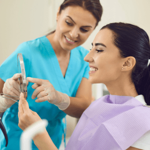 Female dental patient looking in handheld mirror smiling regenerative treatment options in Schererville, indiana