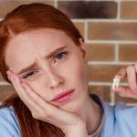 Woman holding the side of her face in pain due to wisdom tooth complications